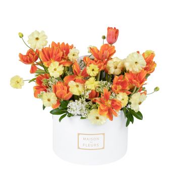 Bursting into spring with vibrant orange tulips accompanied by the fluffiest yellow and white flowers in our popular round box