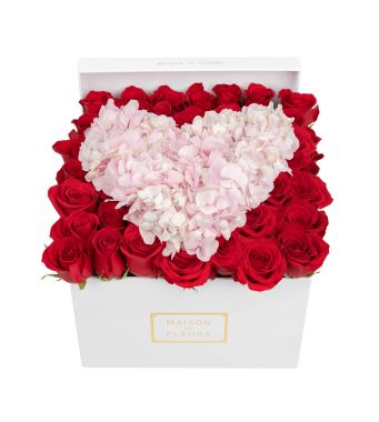A romantic heart of pink flowers arranged on a bed of red roses